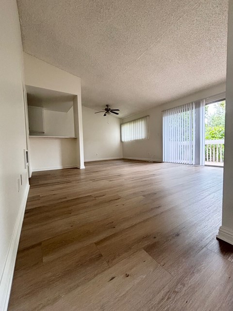 an empty living room with wood flooring and a ceiling fan